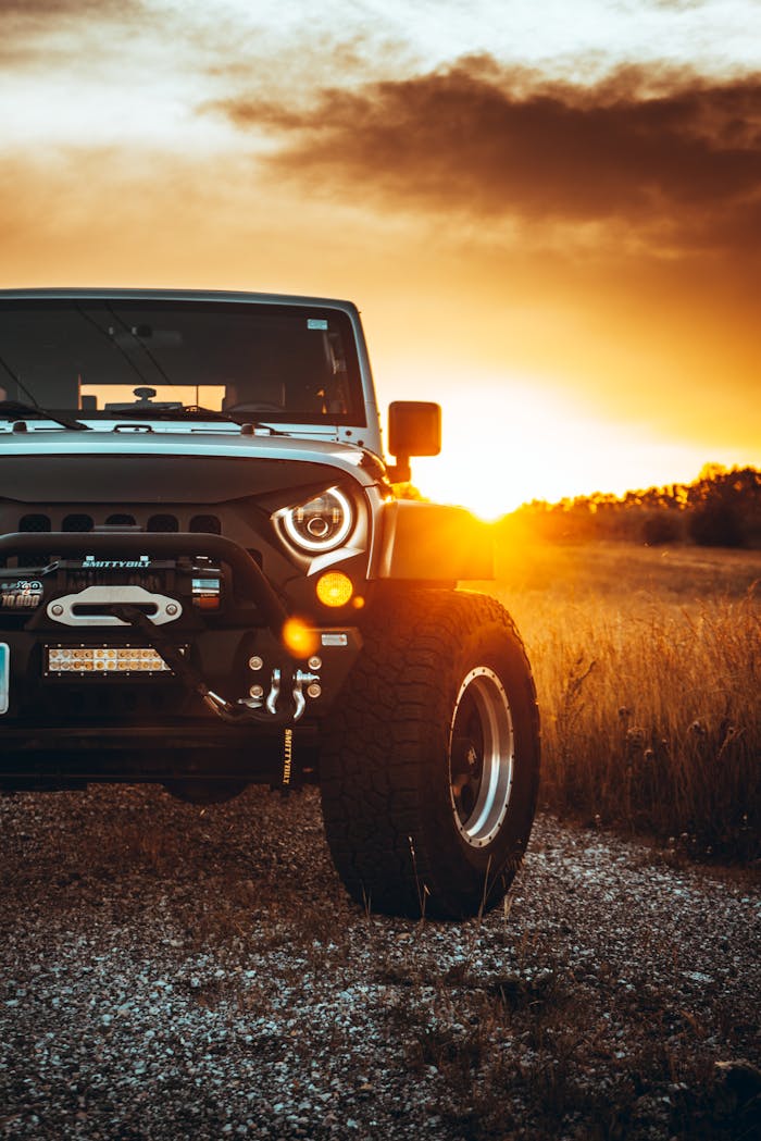 A rugged Jeep SUV parked on a dirt road during a vibrant sunset, highlighting adventure and exploration.